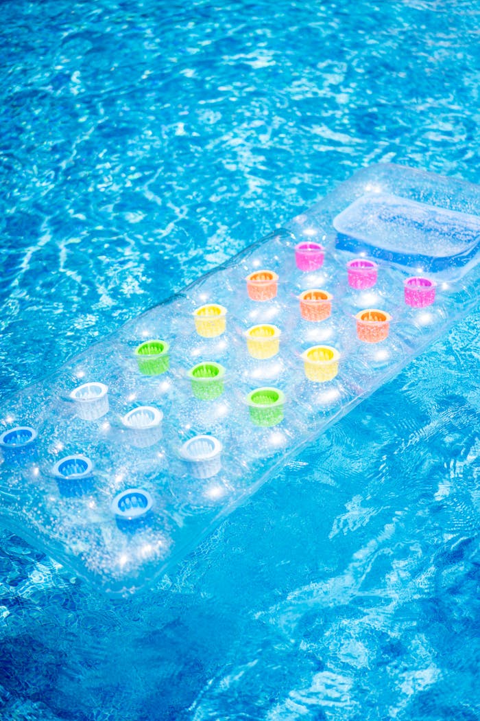 services-03 Vibrant inflatable mattress floating in a clear blue swimming pool on a sunny day.