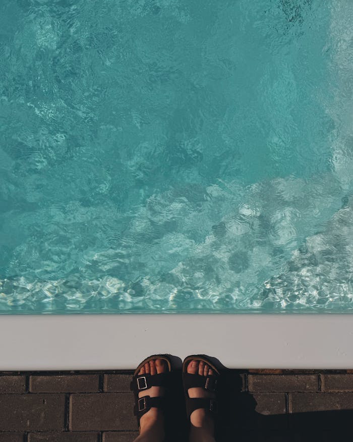 about-us-02 Charming poolside view with feet in sandals. Perfect summer vibe.